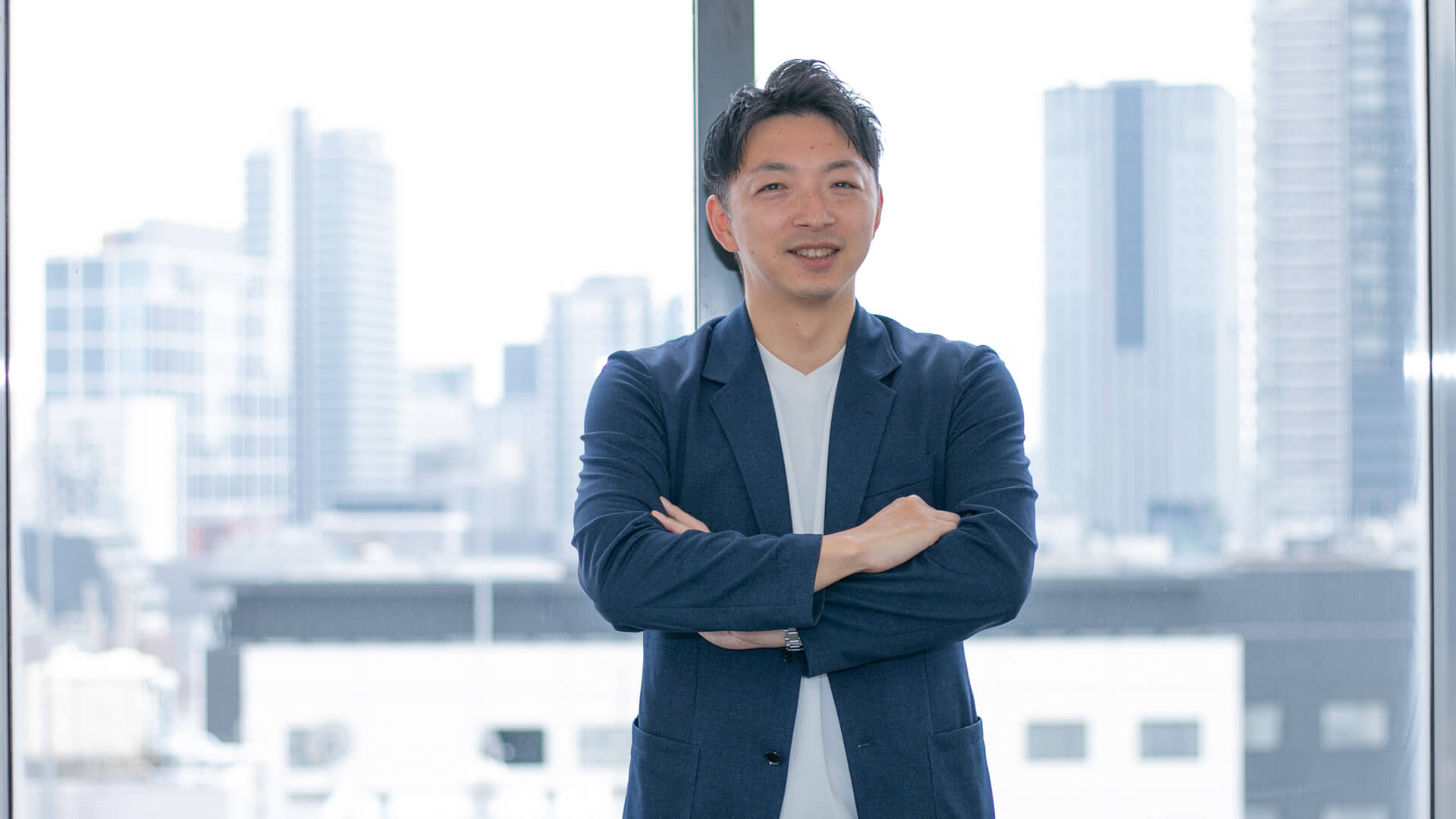 腕を組んで微笑んでいる男性の様子